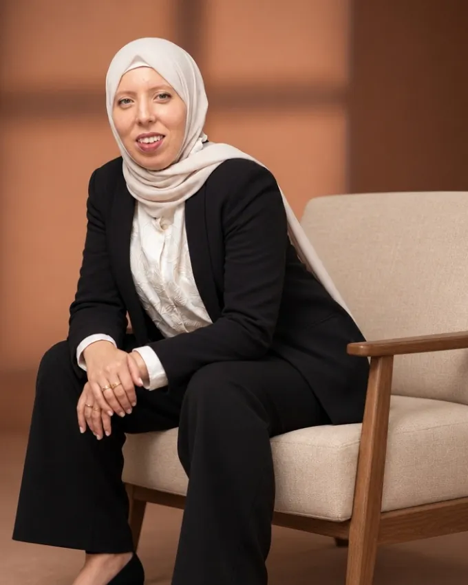 Amina Ouadday, ingénieure process & IA, assise dans un fauteuil, en tailleur noir